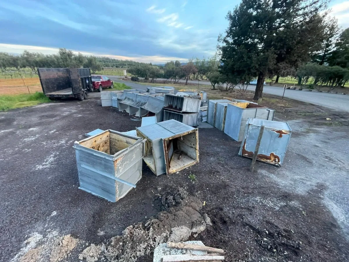 Dismantled metal ductwork beside a truck and trailer
